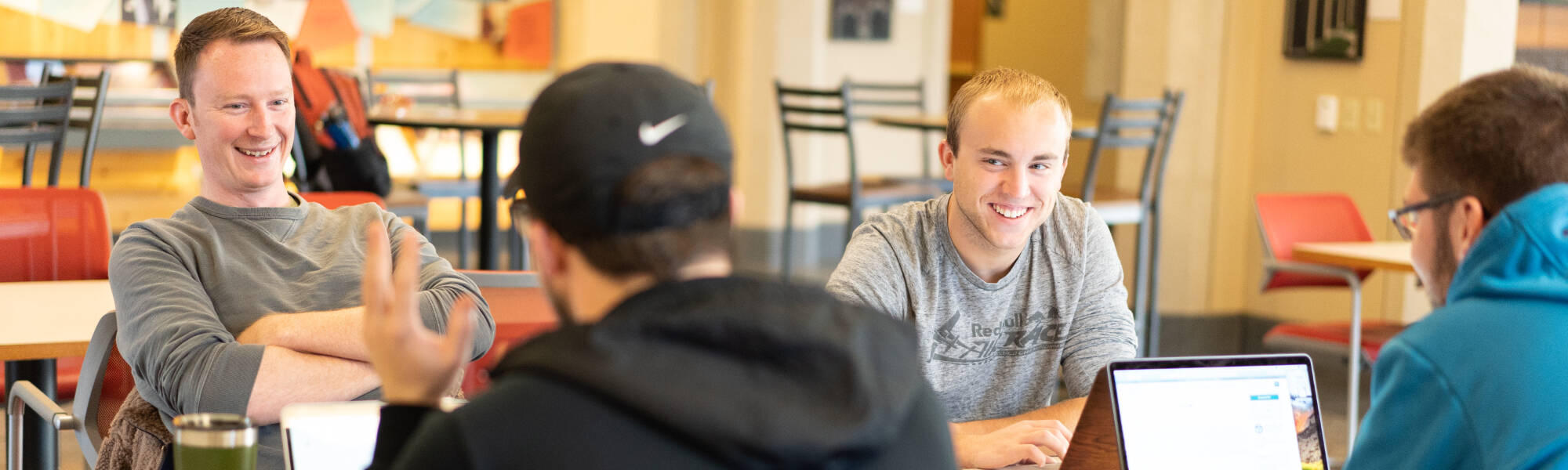 Four students laughing at a table together